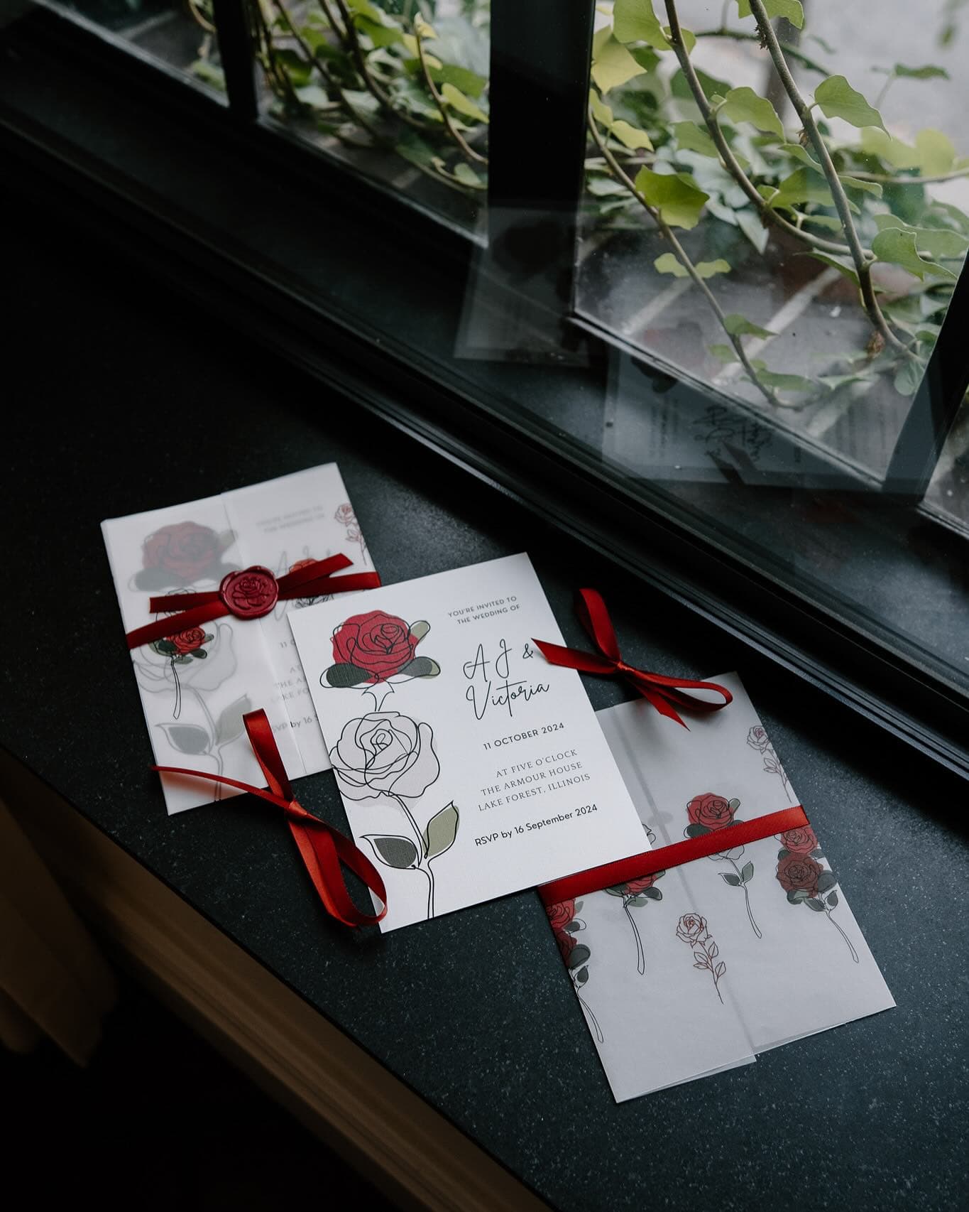 Rose-themed wedding invitation suite with red ribbon and wax seal