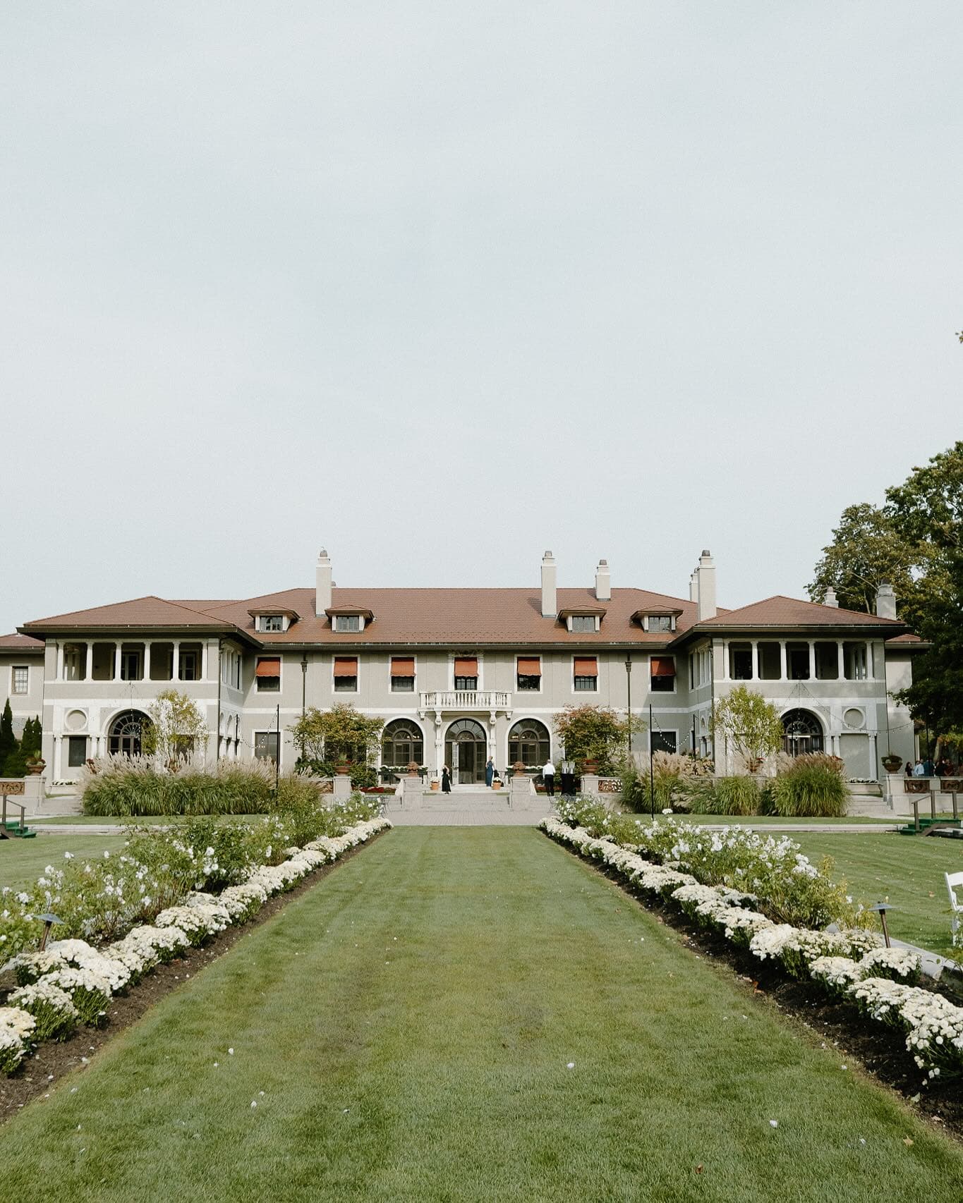 Grand estate venue with manicured gardens and flower-lined walkway